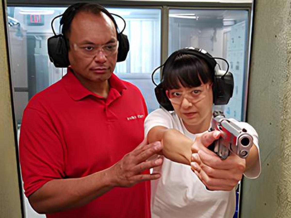 a man teaching a woman how to fire a gun at 808 gun club in honolulu, hawaii